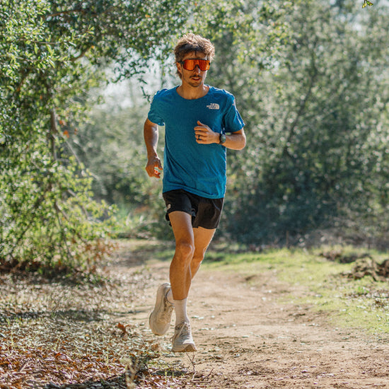 A man wears the Smith Wildcat sunglasses while out for a trail run under the trees.